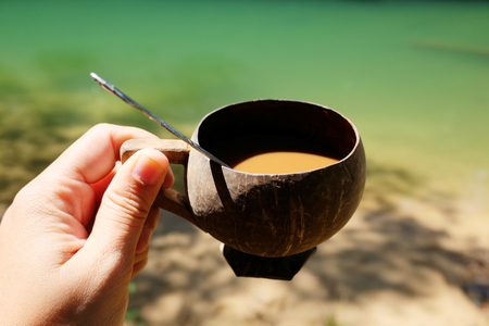The Morning coffee in the glass from natural coconut shells on woman handsの写真素材