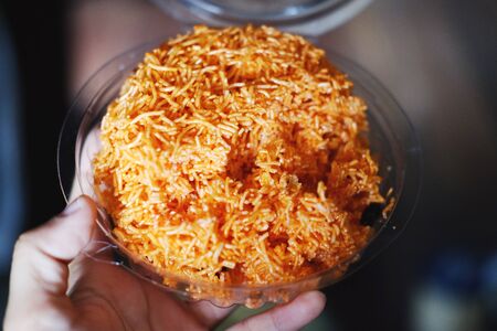 Hand holding Sweet & Sour crispy rice noodle vermicelli in clear plastic box