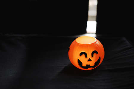 Smiling Halloween pumpkin head on black clothes in natural shadow and sunlight. Halloween holiday concept.の写真素材