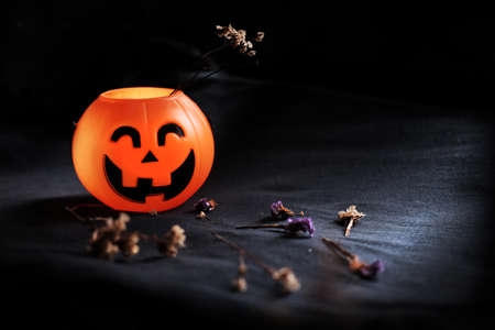 Halloween pumpkin head with dry flowers on black clothes in natural shadow and light. Halloween holiday concept.の写真素材