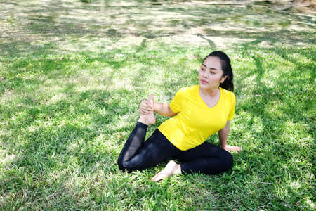 Smiling Asian young woman in black sportwear resting and tying Shoelace on wooden bridge before exercise and running in the garden.の写真素材