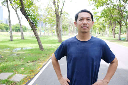 Smiling Asian man relaxing and refreshing after excercise and running in the parkの写真素材