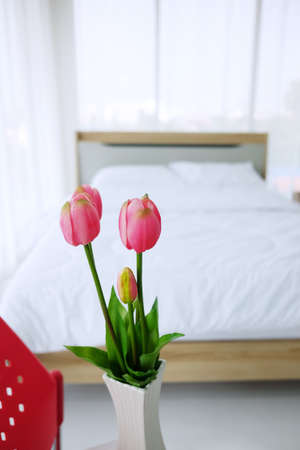 Blooming Pink tulips flower in a white ceramic vase decoration in bedroom