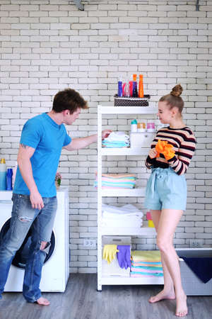 Young Caucasian couple love husband and wife choosing house cleaning equipment on white shelf for do housework together in kitchen room. Lifestyle of Family and married on Holiday Conceptの写真素材