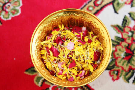 Red rose and Marigold flowers petals in gold tray in tradition Thai wedding ceremony and Buddhism in...