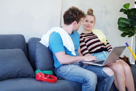 Smiling Young Caucasian couple love relaxing with laptop online for community in social media for...