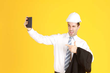 Handsome smart engineer or architecture is Wearing a white safety hat with hand holding smartphone...