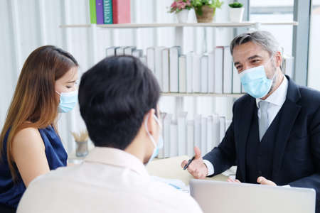 Caucasian Senior manager meeting with asian teamwork and businesspeople wearing mask preventing for...