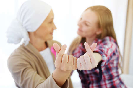 Caucasian Mother and young daughter making Mini heart hand for love with caring and encouragement for elderly mother is suffering from cancer or Leukemia patient after chemotherapy. Focus on fingersの写真素材