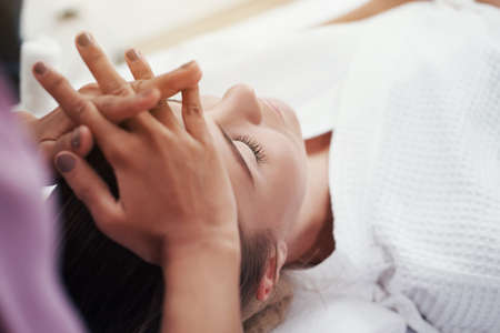 Closed up Asian Massage therapist woman hands is making traditional head and facial treatment...