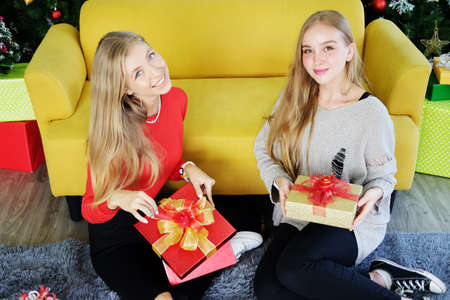 Smiling of Teenage. Caucasian couple girls sitting on the floor and holding big Gift boxes in...
