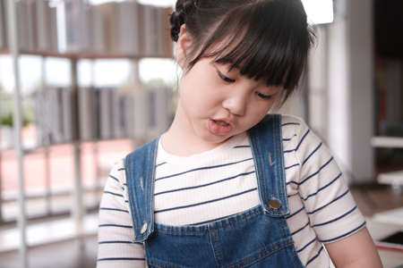 Smiling asian little girl child is playing and talking by herself in living room.の写真素材