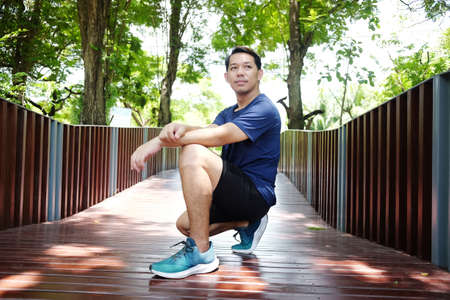 Smiling handsome Asian man relaxing and refreshing after excercise and running in the garden.
