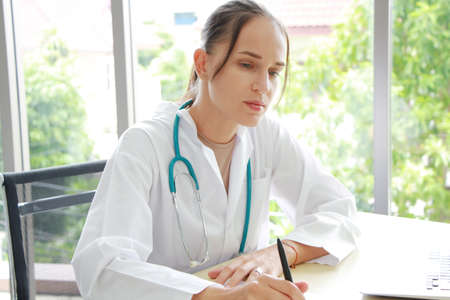 Professional Caucasian Female Psychiatrist is Studying and researching on website with laptop for treament patient at workspace. Major depressive disorder patients and healthcare Concept.の写真素材