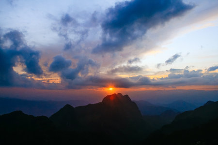 Sunset in sky and cloud, beautiful colorful twilight time with silhouette of mountain.の写真素材