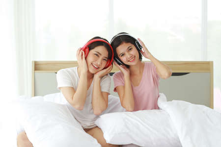 Asian young sisters lovely couple on white listen to music with Headphones and dancing together in...