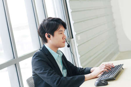 Businessman Call Center and technical Support staff with headset talking and serious with job. Asian...