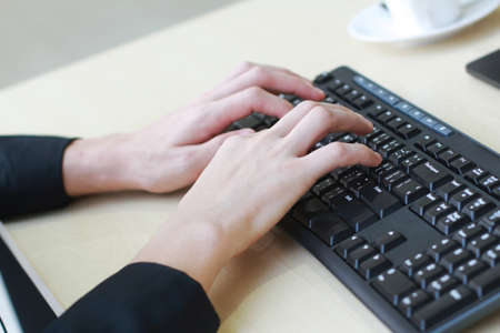 Close up on asian businessmen hands typing Keyboard with a cup of coffee on computer desk in office