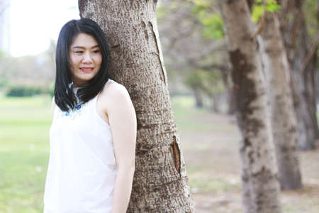 Beautiful asian woman in white dress relax and smiling in natural park. Young Thai girl enjoy on holiday with sunlight in garden.の写真素材