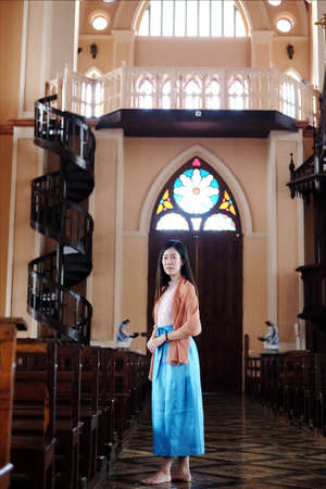 Asian woman is standing a Christian church for make a wish and pray for hope and encouragement in life. Rituals and beliefs in Christian of Thailand concept.の写真素材