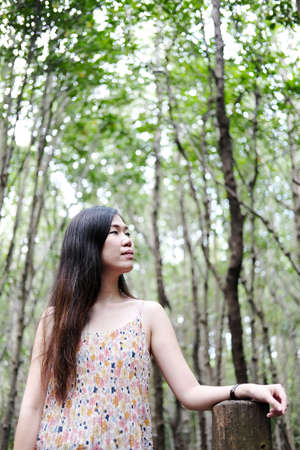Pretty Asain girl is smiling and sitting on wooden bridge in the tropical mangrove forest at...