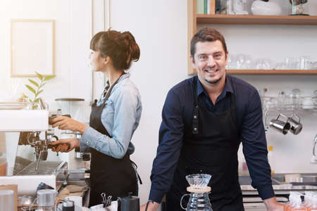 Smiling Caucasian Young barista couple love is wearing apron and working in the coffee shop. Start...