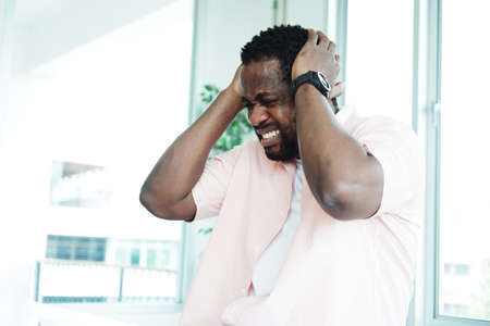 Young African Businessman is online working with internet on laptop at office. He is serious and...