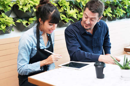 Smiling Caucasian Young barista couple love or partnership is wearing apron and consulting for...