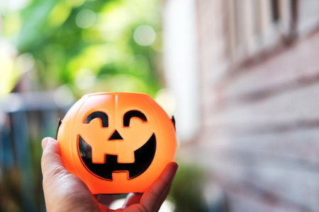 Hand holding halloween pumpkin head with golden light in dark night bakckground. Halloween holiday concept.の写真素材