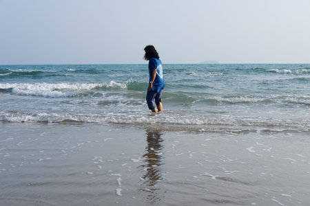 Happiness of Asian woman joyful with sea and wave on the sand beach in sunset. Freedom lonely life on vacationの写真素材