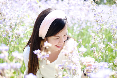 Beautiful Asian woman is smiling and relaxing in blooming purple Murdannia giganteum flowers fieldの写真素材