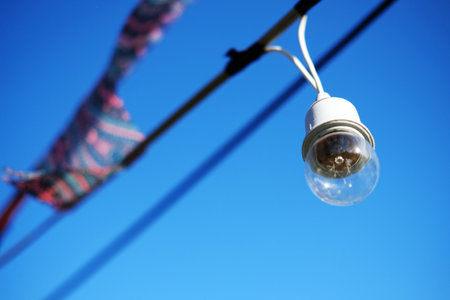 Equipped and electrical with light bulbs is hanging in the wind and sunlight on blue sky