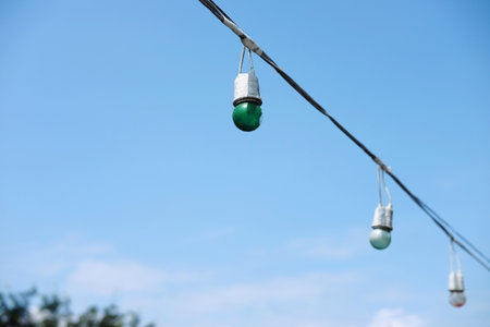 Equipped and electrical with light bulbs is hanging in the wind and sunlight on blue skyの写真素材