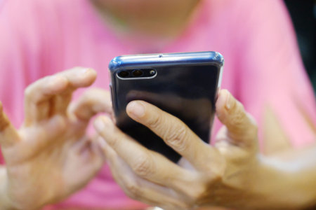 close up hand elderly asian woman is holding smartphone and searching on website for internet....