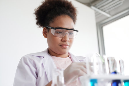 Smiling African American girl student is holding test tube chemical and science for experimenting at...