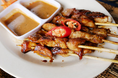 Close up BBQ food or barbecue grilled chicken with dipping sauce and red chili pepper vegetable on white dishの写真素材