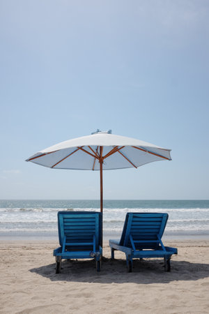 Couple lounge chairs under white umbrella on sand beach and tropical calm sea in sunny day on summer in Asianの写真素材
