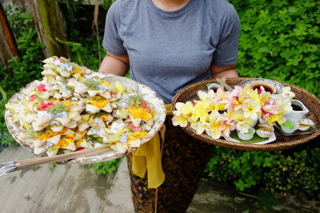 Close up Balinese woman holding flower and sacred offerings in woven basket of Hindu beliefs in Bali at Indonesiaの写真素材