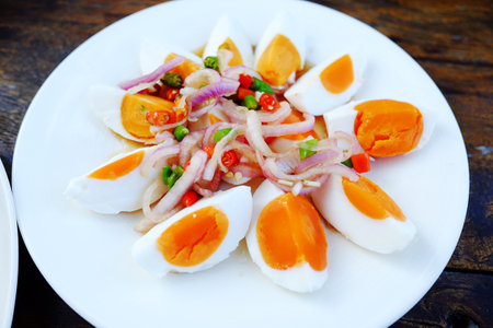 Spicy soft boiled egg salad in white dish. Tradition food of Thailandの写真素材