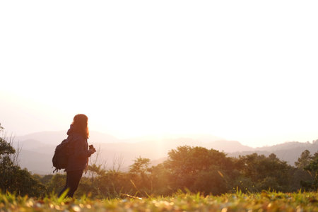 Asian young woman backpack holding camera and standing with wildflower and beautiful landscape of valley Doi Luang Chiang Dao mountain, Chiang Mai Province of Thailandの写真素材