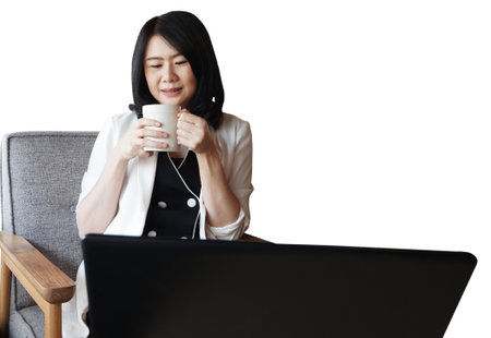 Smiling professional Asian businesswoman in white suit drinking a cup of hot coffee and working or shopping with laptop. People with technology concept isolated on white background with clipping pathの写真素材