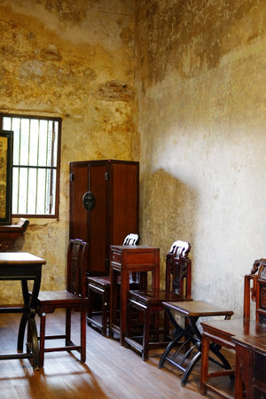 Old wooden cabinet and chair furniture of Chinese style in vintage and rustic grunge concrete wall in literature room with natural sunlight in Bangkok of Thailand. Vertical Photoの写真素材