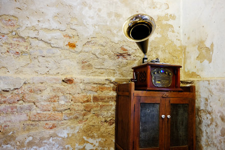 Vintage wooden Gramophone music box on antique wooden cabinet inside grunge concrete and brick wall in Bangkok of Thailand. Copy spaceの写真素材