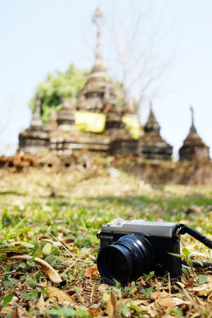 Vintage camera on green lawn grass in ancient old pagoda and temple background. Travel in Thailandの写真素材