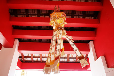 Beautiful handmade culture golden paper lantern hanging and blowing decorated on red ceiling in the temple of Thailandの写真素材