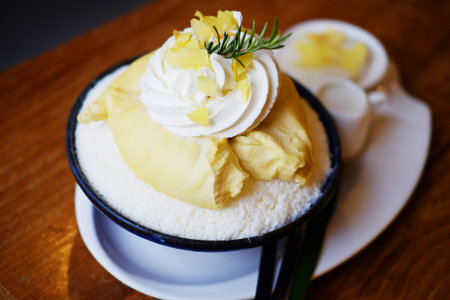 Fresh Bingsu Durian and ice cream with whipped cream served with condensed milk in a bowl on wooden tableの写真素材