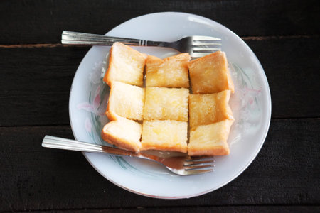 Homemade toast or bread with butter topping in white dish with forks on wooden tableの写真素材