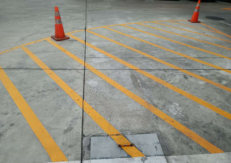 Yellow traffic lines and orange cones, no-parking areas.の写真素材