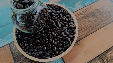 Top view coffee beans from a glass bottle on a wooden plate