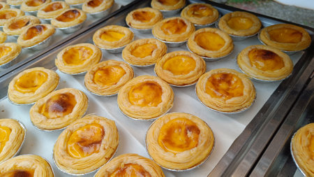 Golden brown egg tarts on a tray delicious dessertの写真素材